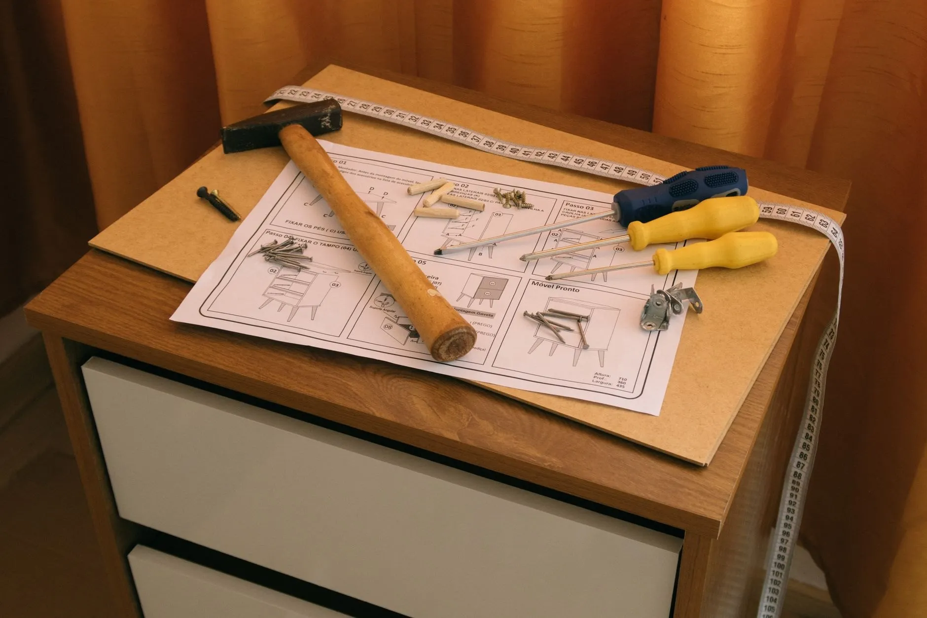 Assembly instructions and hand tools resting on a half-built bedside cabinet