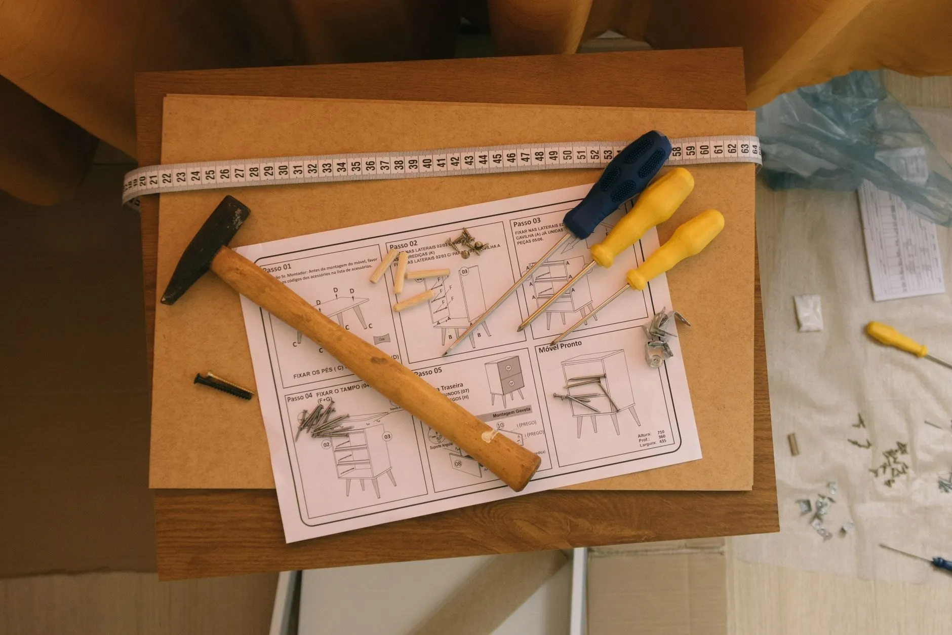 A hammer, screwdrivers, dowels and a tape measure on top of a flat-pack instruction sheet